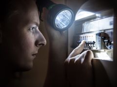 Man restoring power on circuit breaker after electricity outage